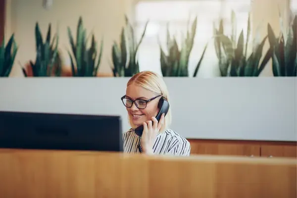 Blonde Frau am Telefon am Empfang