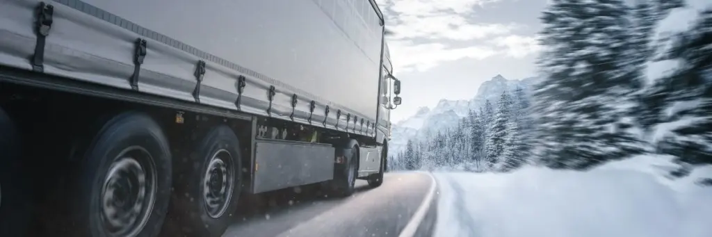 LKW fahrend auf einer Straße im Schnee